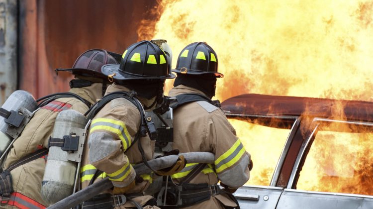 car on fire and firefighters spraying water